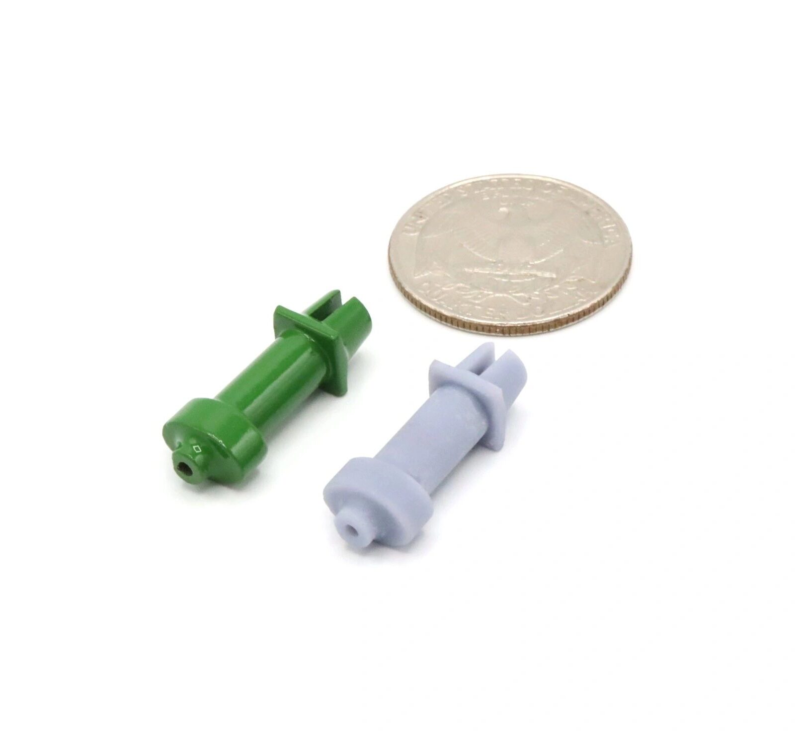 Small green and gray plastic wall anchors next to a coin for scale.