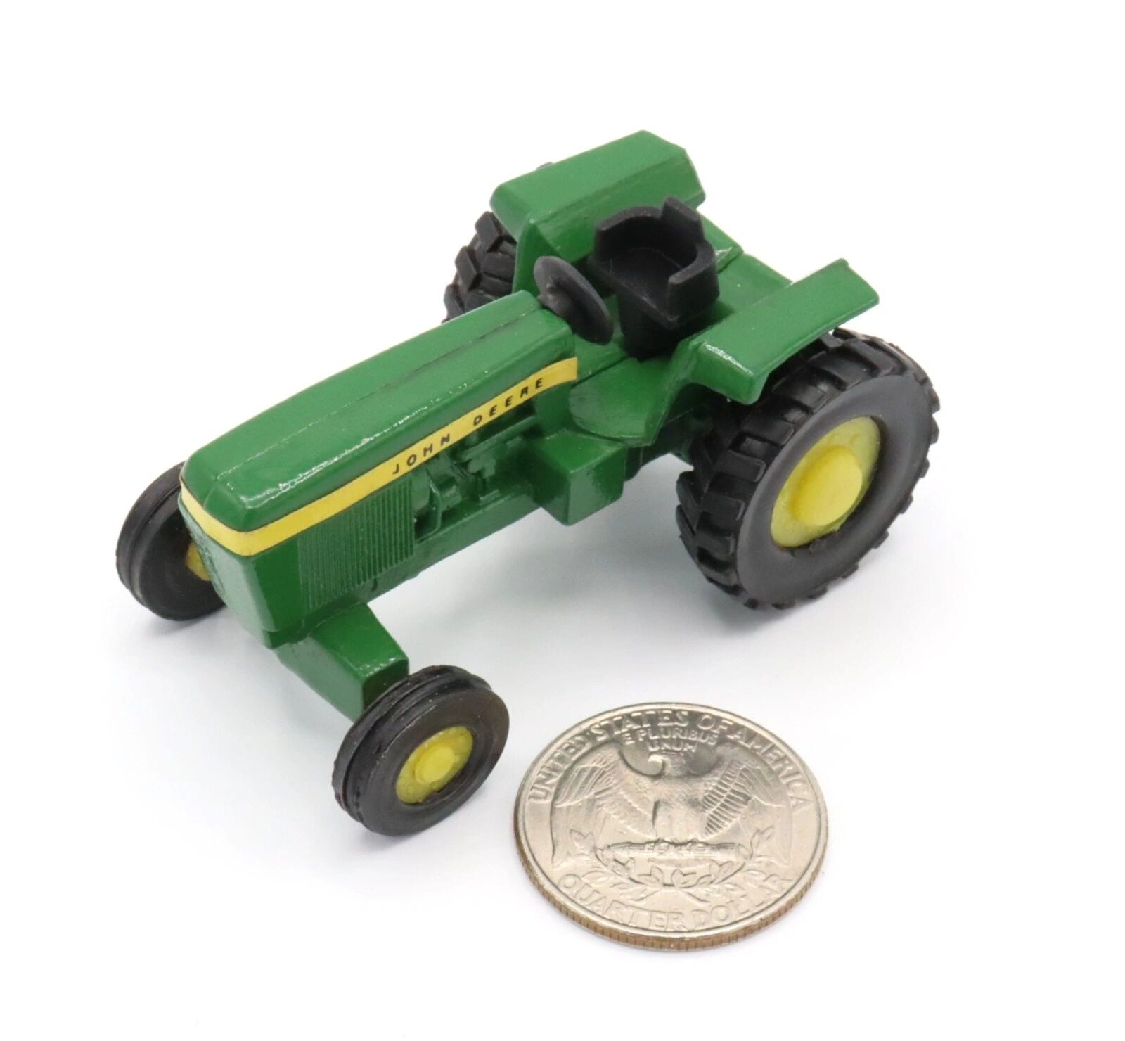 A small green toy tractor next to a coin for scale.