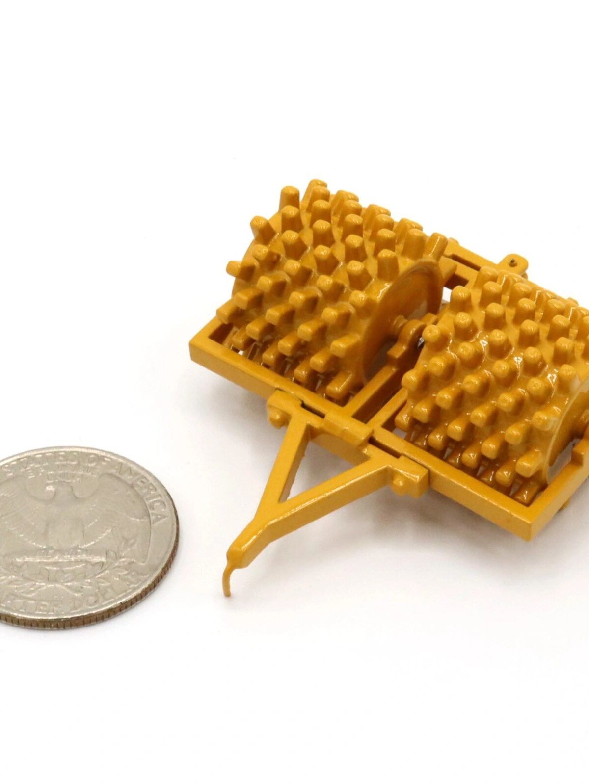 Small brown plastic waffle-shaped object next to a coin for scale.